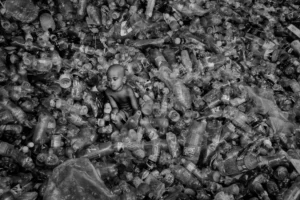 A boy photographed in between a mountain of plastic bottles.