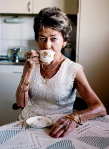 Analog photo of an old lady sipping tea, taken by photographerMartina Holmberg